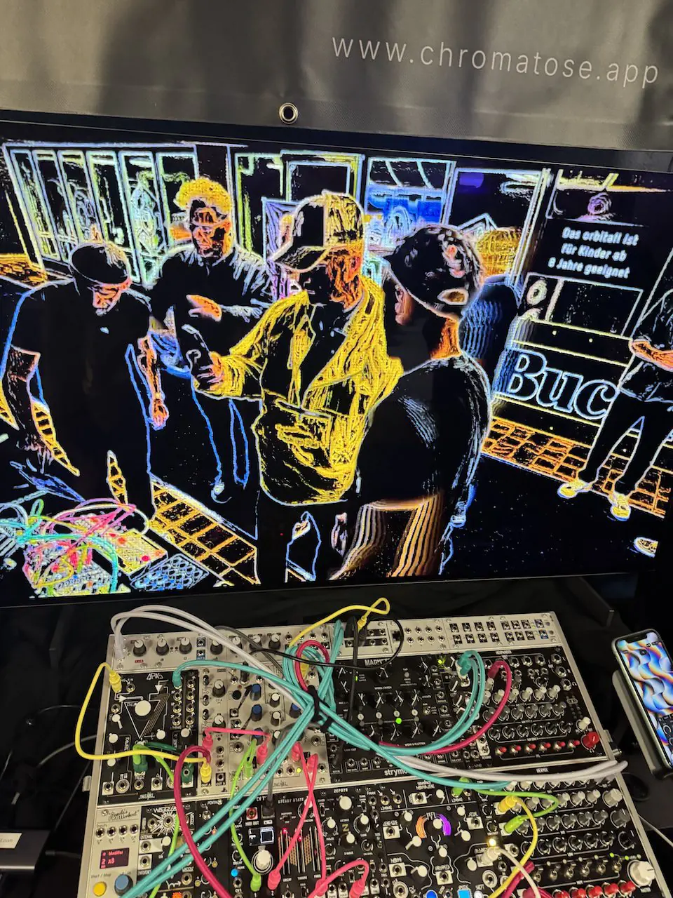 Chromatose turning a live camera feed of booth visitors into real-time visuals, with a Eurorack modular synthesizer below